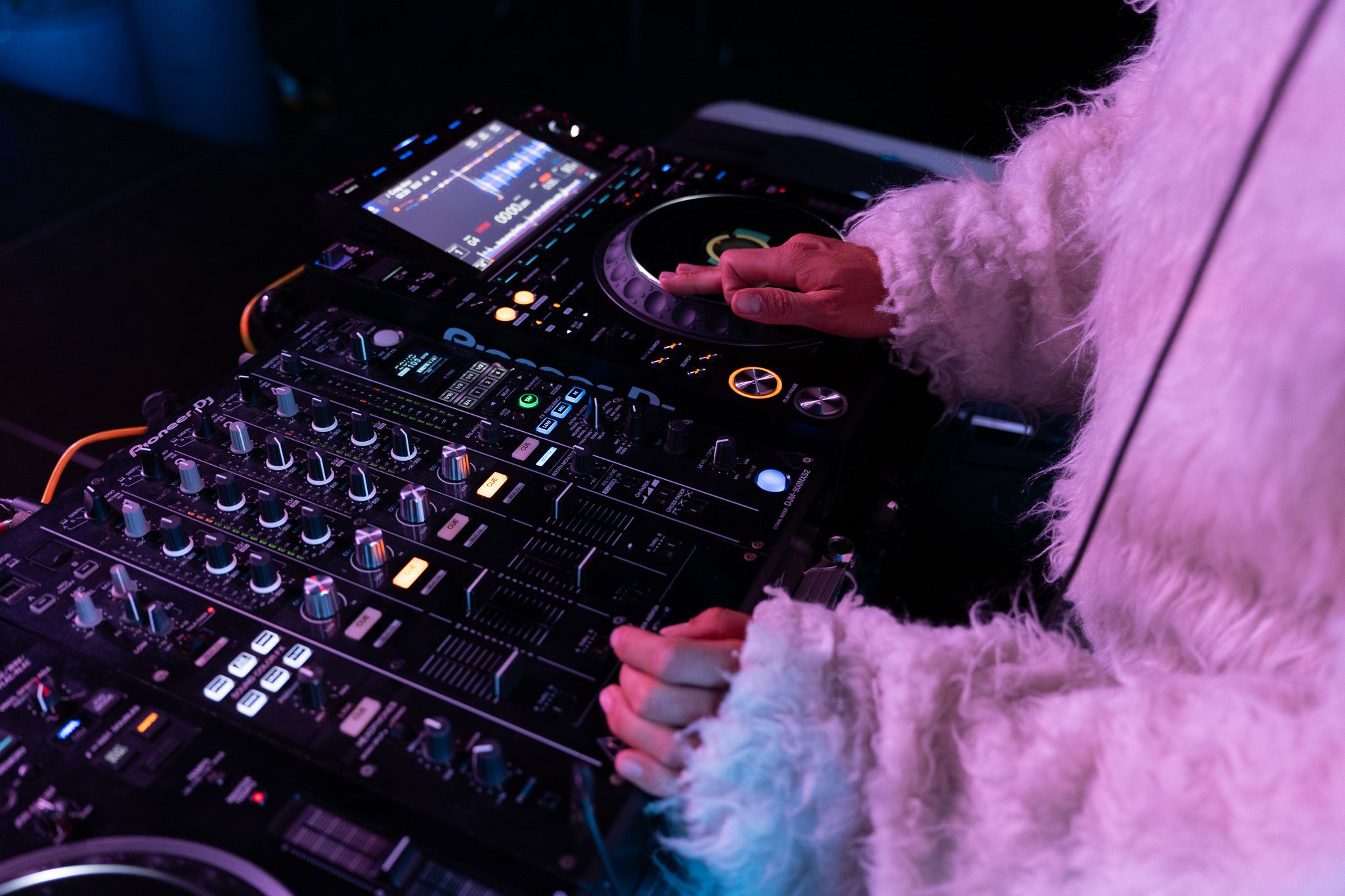 Bass Bunny's hands in white fur sleeves on the DJ decks and mixer